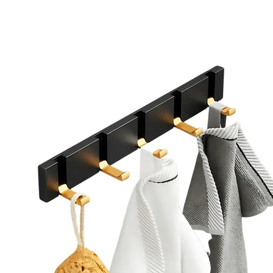 Cabide Velutta de parede preto e dourado com toalhas dobradas, elegante e funcional
